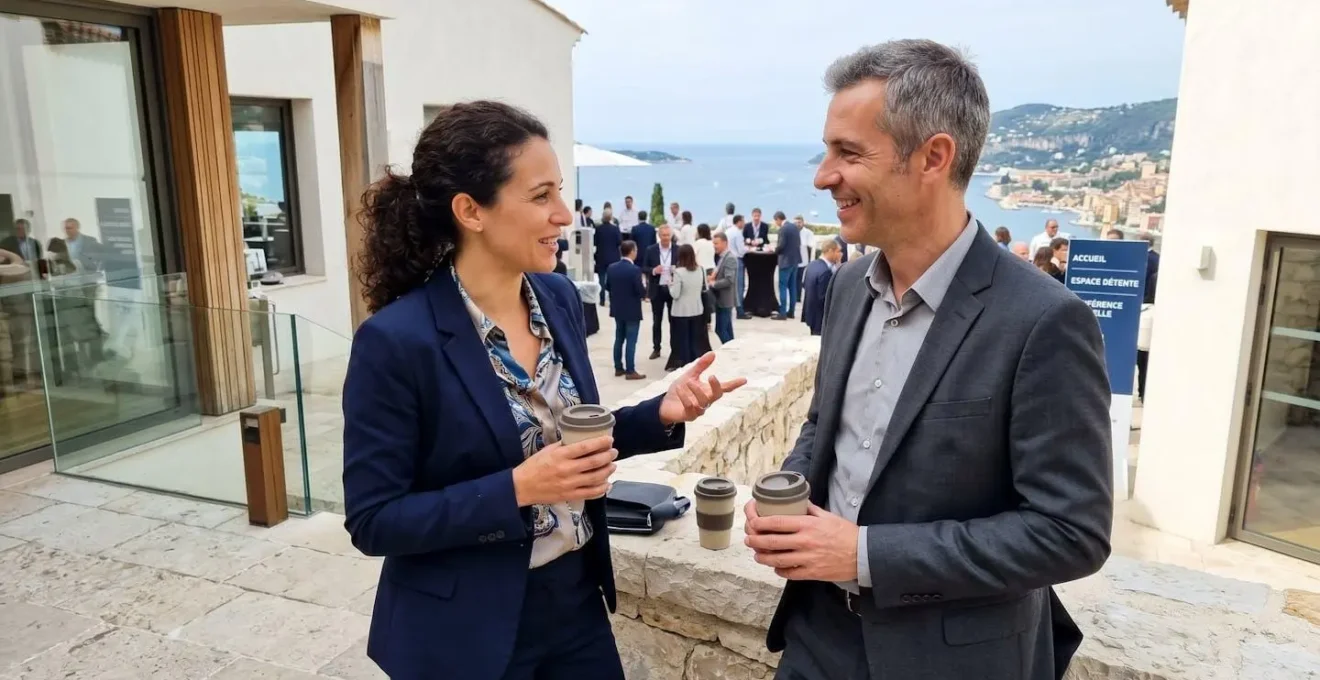 Deux collaborateurs échangent de façon informelle lors d'une pause dans un lieu de séminaire contemporain à architecture méditerranéenne
