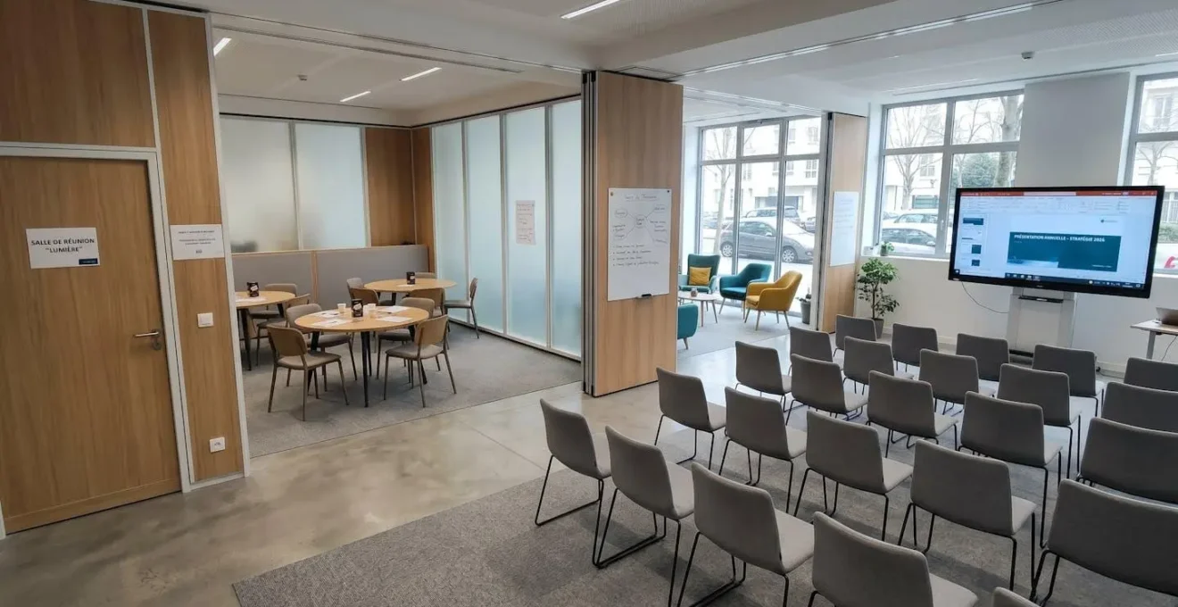 Salle de séminaire modulable avec plusieurs configurations possibles : espace plénière, tables de travail en sous-groupes et zone détente informelle